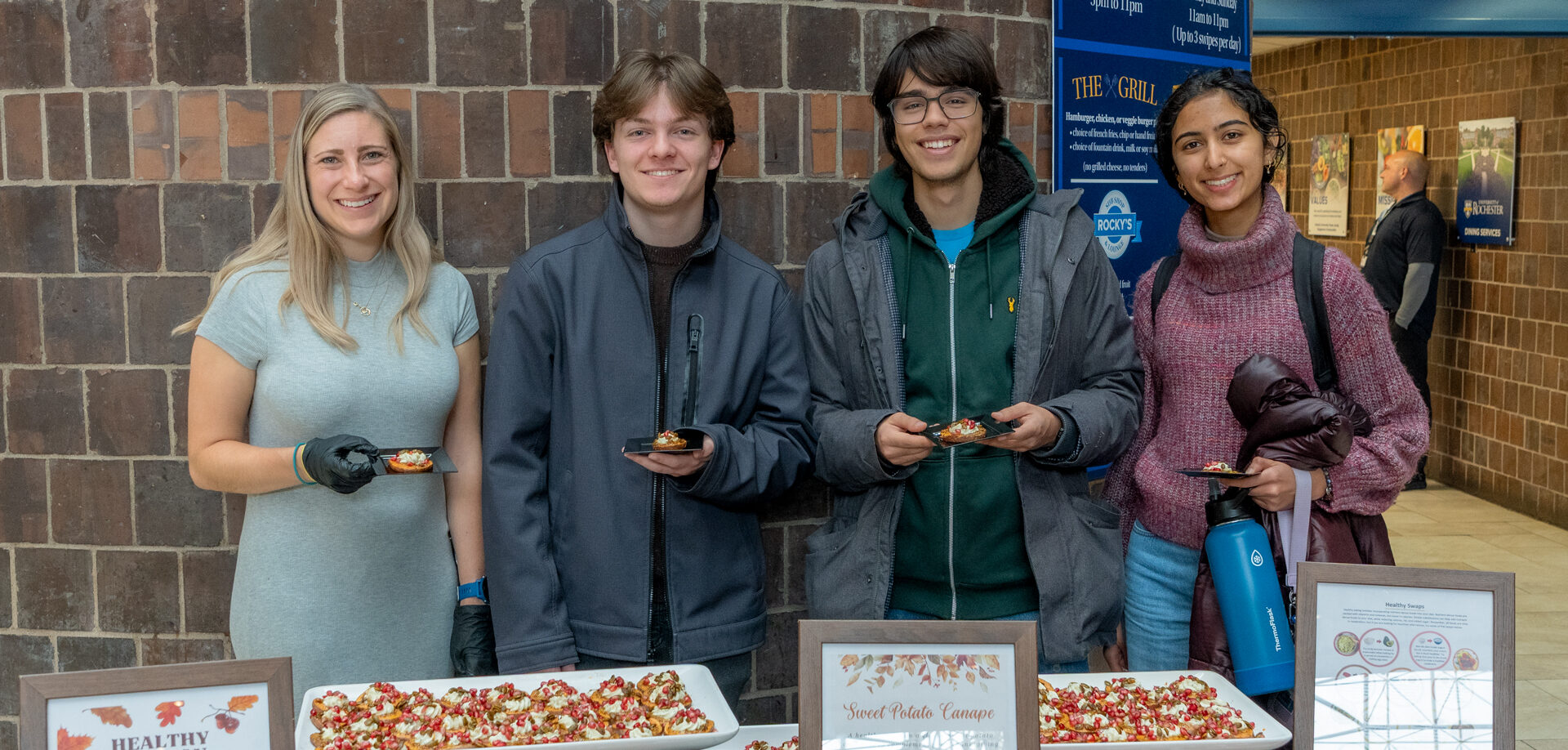 Image shows four people standing behind a catered table